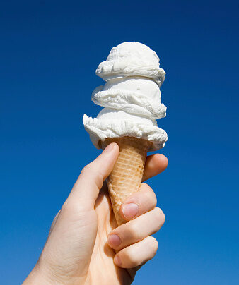 triple scoop vanilla ice cream cone in hand