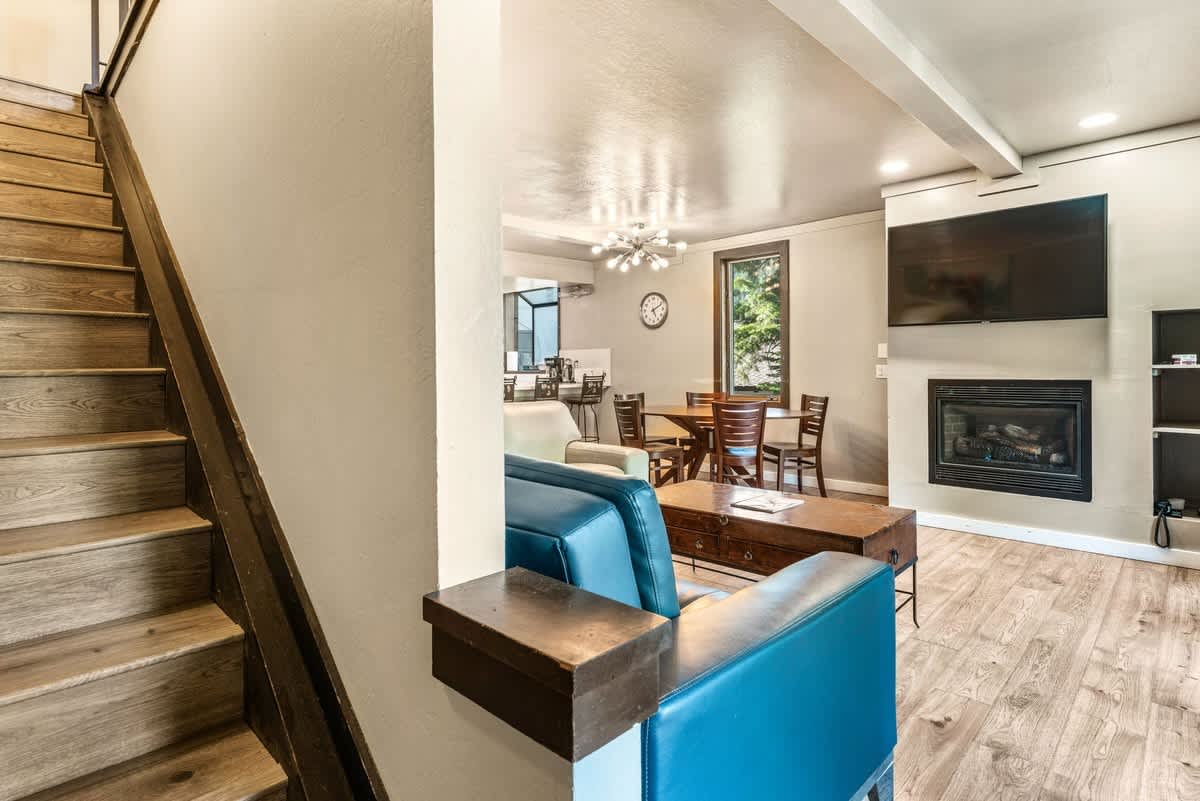 Modern living area in Olympic Valley vacation rental, featuring a fireplace, flat-screen TV, and dining table.