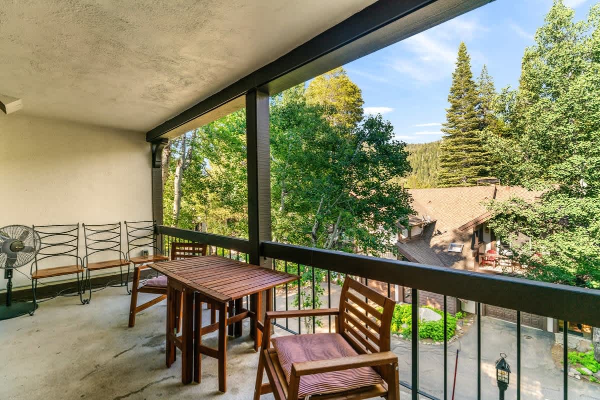 Balcony view of trees and houses from a vacation rental in Olympic Valley, featuring outdoor seating and a peaceful setting.