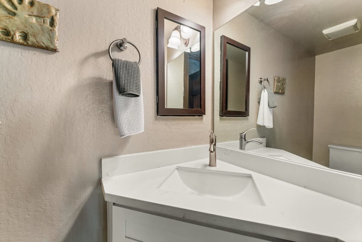 Modern bathroom in Olympic Valley vacation rental, featuring a triangular sink, mirror, and wall-mounted towel.