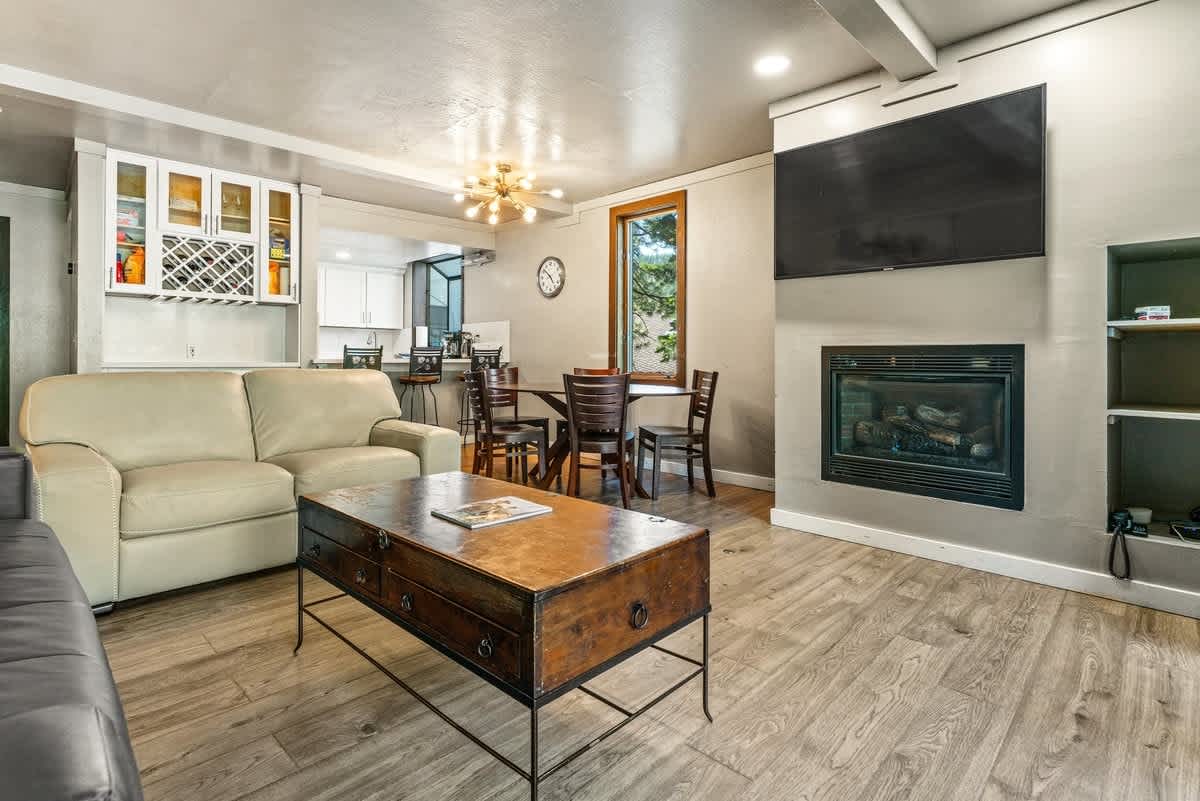 Modern living room in an Olympic Valley vacation rental, featuring a fireplace, leather sofa, and dining area.