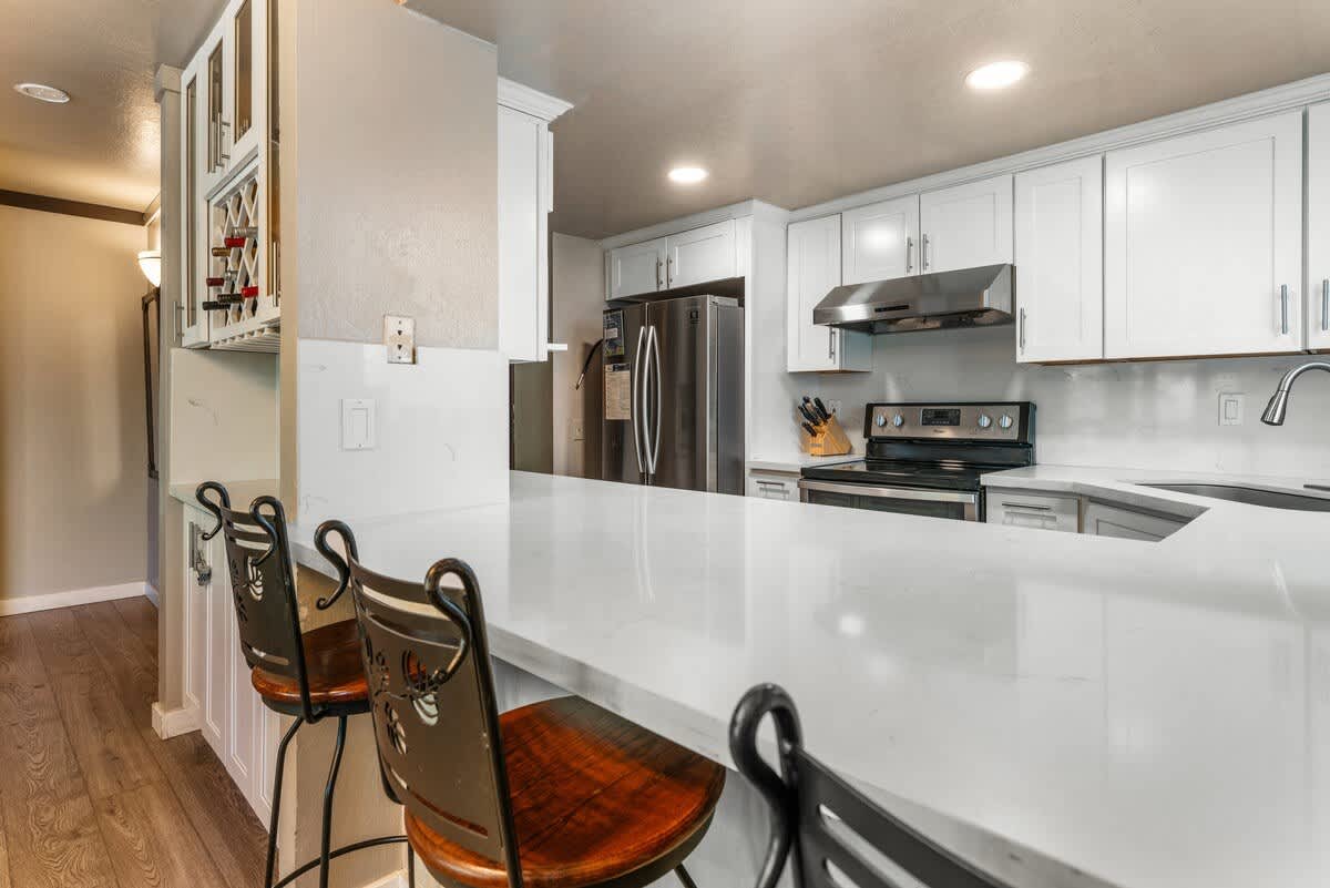 Modern kitchen in an Olympic Valley vacation rental with white cabinets, stainless steel appliances, and bar seating.