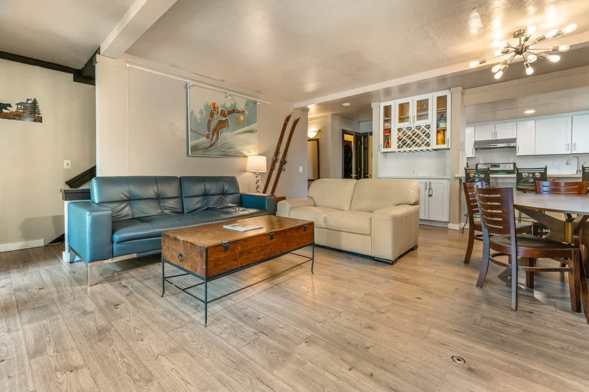 Modern living room in a vacation rental, Olympic Valley. Features cozy sofas, wooden table, and dining area.