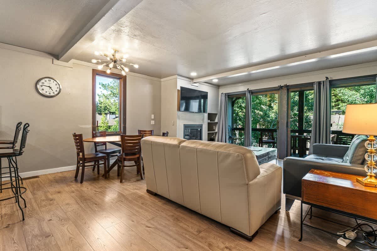 Modern living room in Olympic Valley vacation rental with cozy seating, dining area, and large windows overlooking nature.