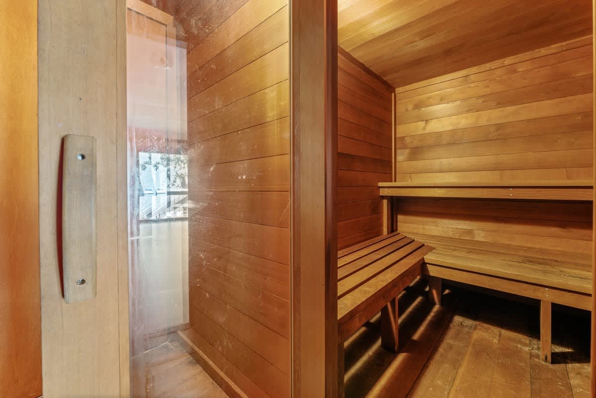 Wooden sauna in an Olympic Valley vacation rental with glass door and bench seating.