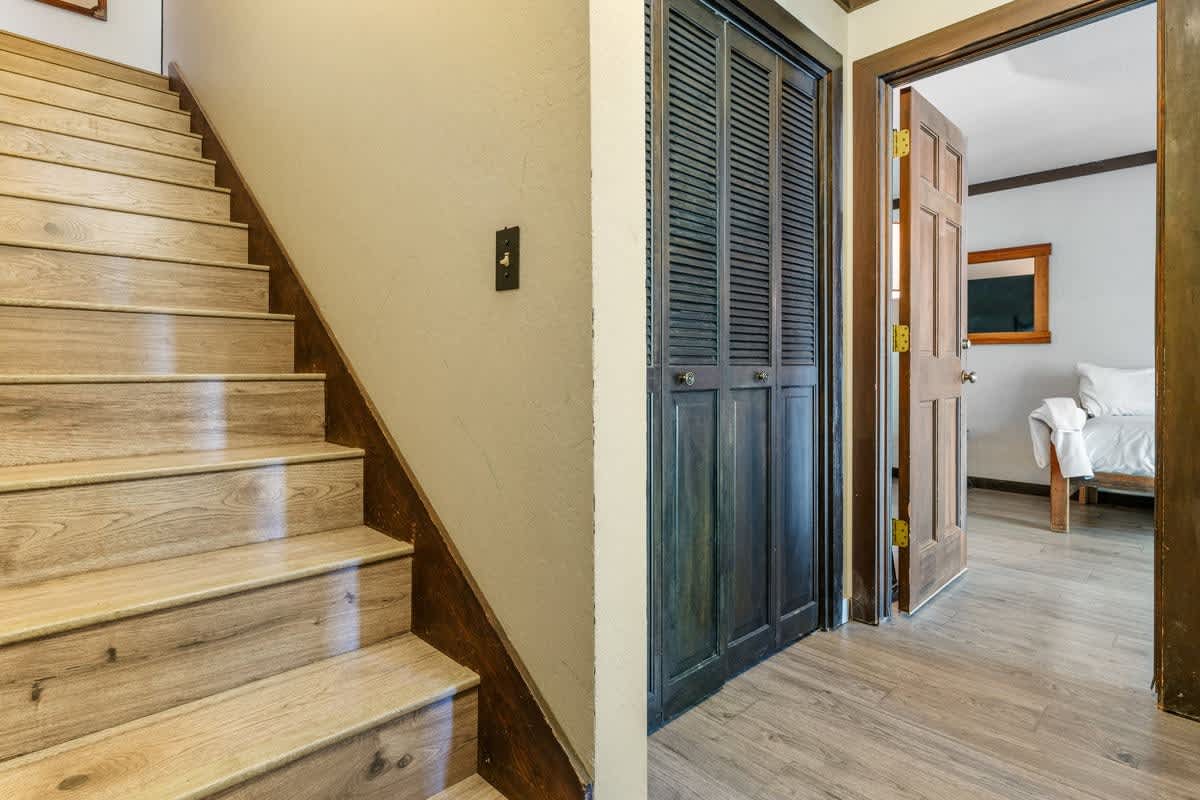 Staircase and hallway in an Olympic Valley vacation rental, featuring wooden doors and flooring, leading to a cozy bedroom.