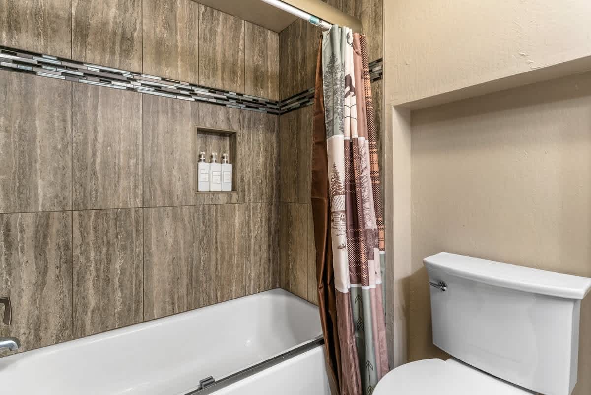 Bathroom in Olympic Valley vacation rental with tiled walls, a shower, and a nature-themed curtain.