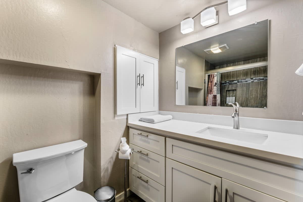 Modern bathroom in an Olympic Valley vacation rental with white cabinets, a sink, and a large mirror.