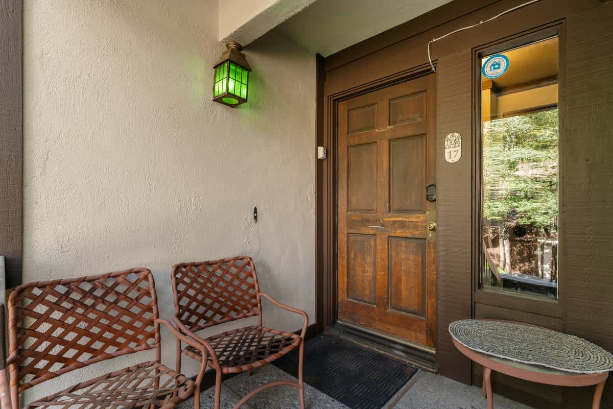 Entrance to a cozy vacation rental in Olympic Valley, featuring two chairs and a wooden door with a green lantern.