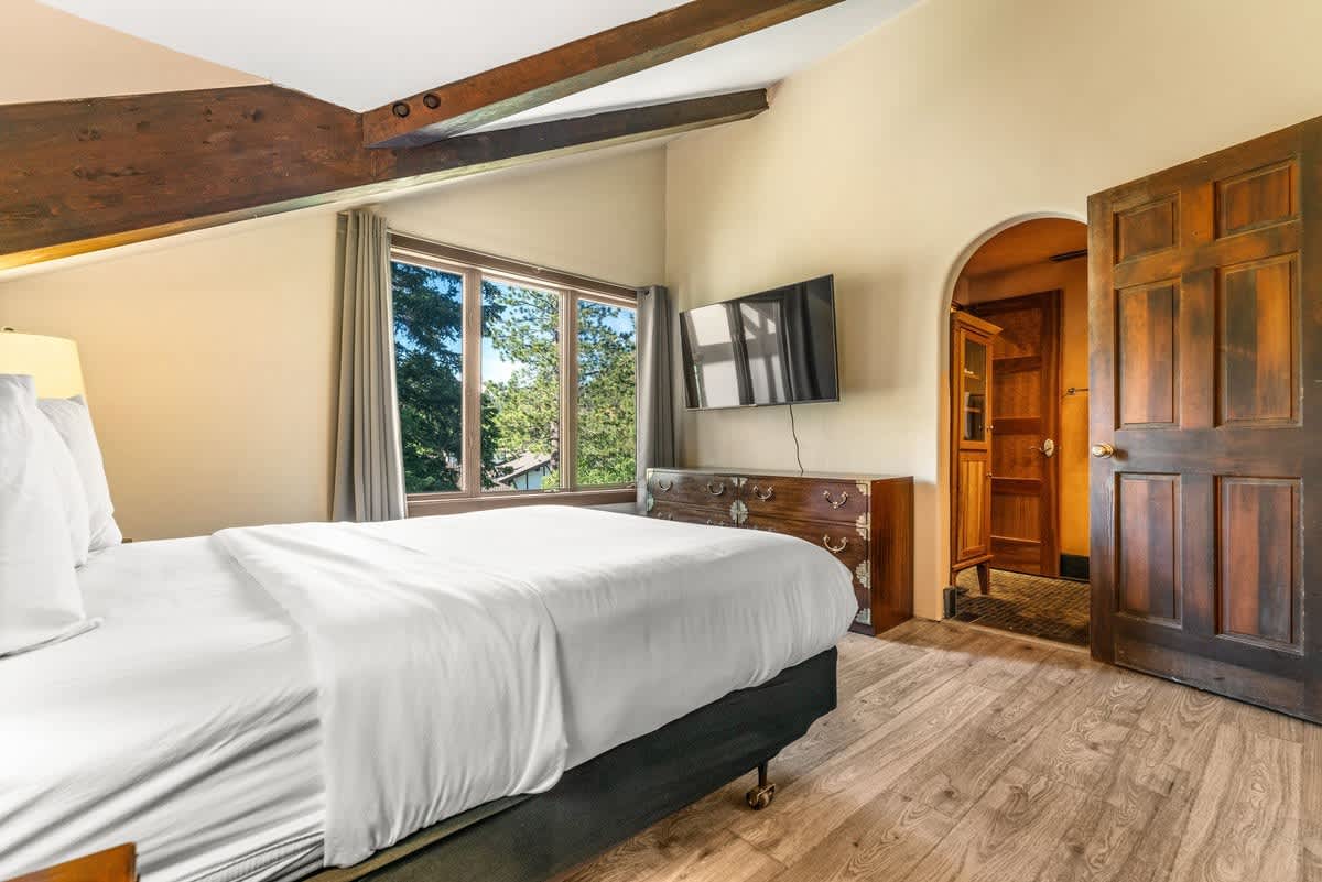 Cozy bedroom in a vacation rental, featuring wooden beams and a scenic window view in Olympic Valley.