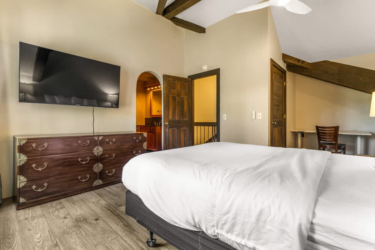 Cozy bedroom in a vacation rental, Olympic Valley, featuring a large TV and wooden dresser, with an open doorway to a bathroom.