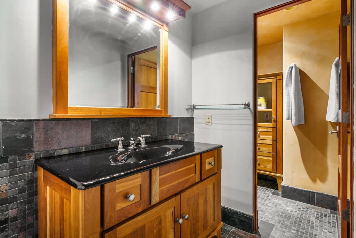 Modern bathroom in Olympic Valley vacation rental with wooden vanity, black countertop, and large mirror.