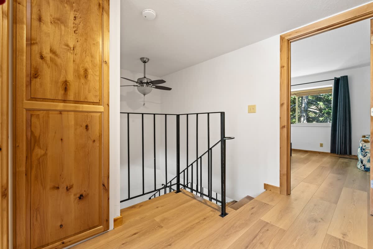 Staircase area in a Tahoe City vacation rental with wooden floors and a ceiling fan visible through a doorway.