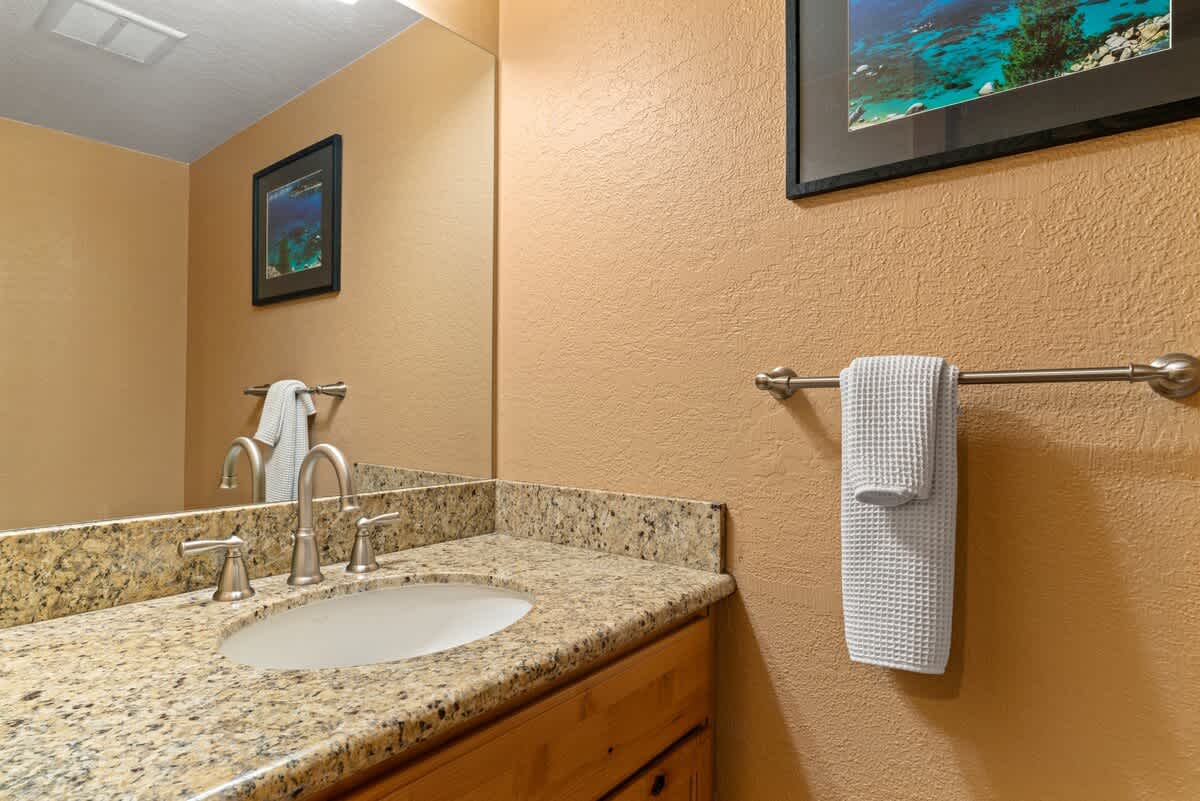 Modern bathroom in Tahoe City vacation rental with granite countertop, mirror, and a towel on rack.