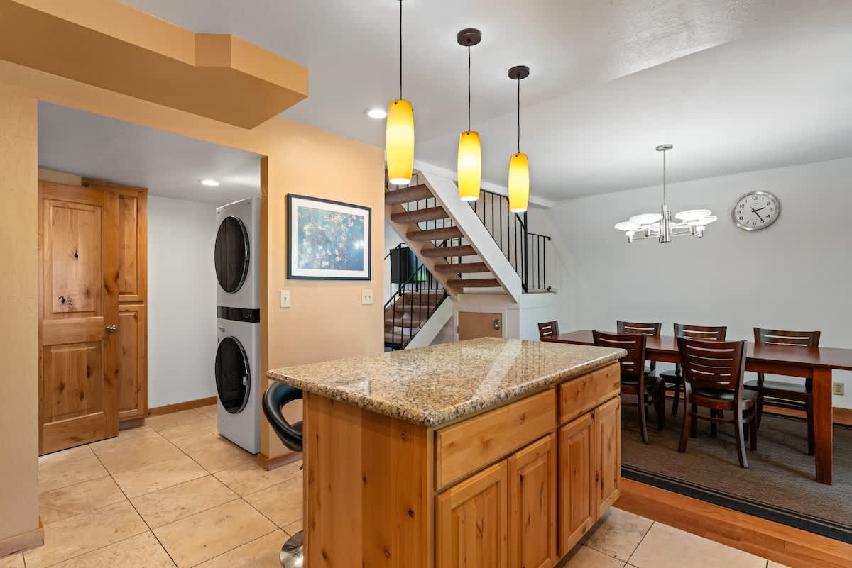 Kitchen and dining area of a vacation rental in Tahoe City, featuring wooden cabinets, a granite island, and modern lighting.