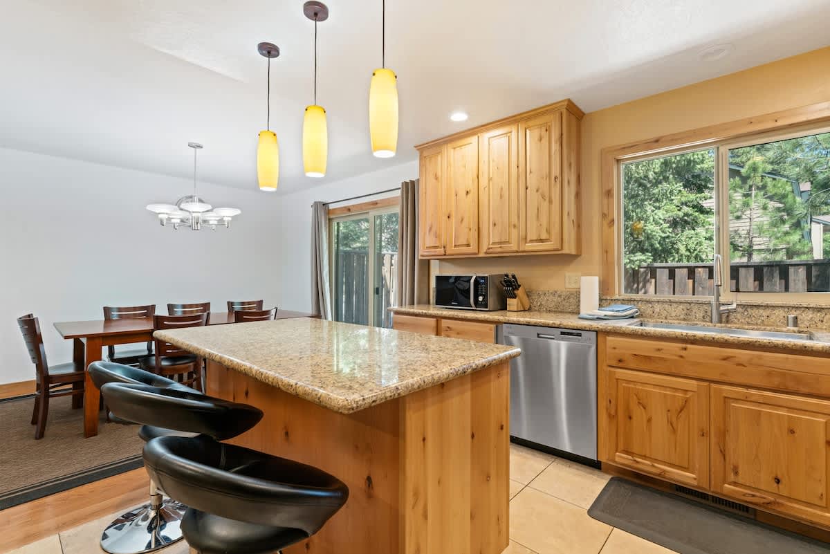 Modern kitchen in Tahoe City vacation rental with wooden cabinets, granite countertops, and a large dining table.