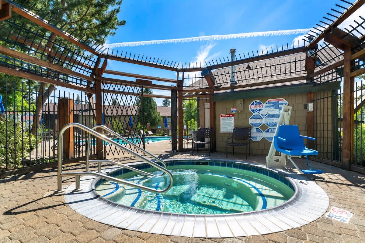 Relaxing hot tub and pool area at a vacation rental in Tahoe City, featuring a trellis and blue skies.