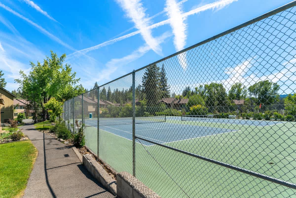 Tennis courts at a Tahoe City vacation rental, surrounded by trees and under a clear blue sky.