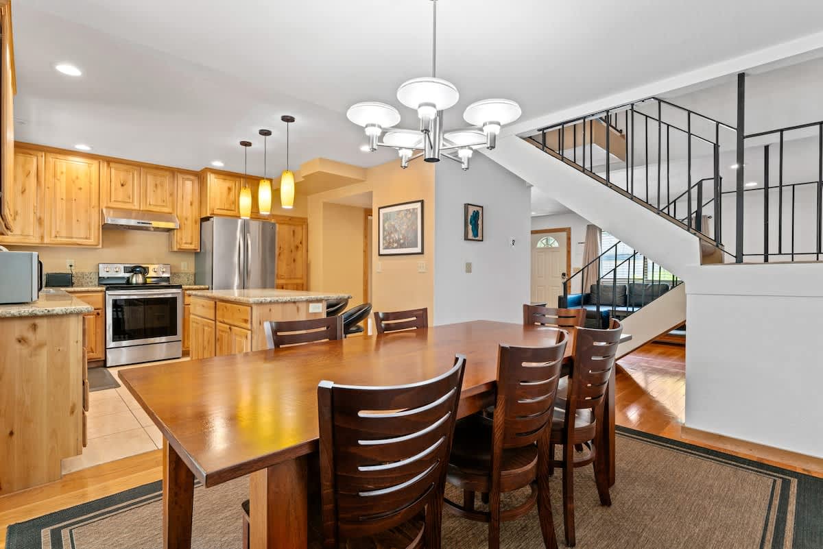 Dining and kitchen area in a Tahoe City vacation rental with wooden cabinets, stainless steel appliances, and a staircase.