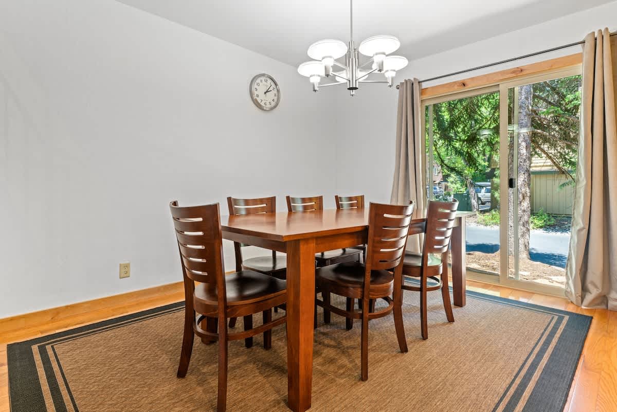 Dining room with wooden table, chairs, and large window in Tahoe City vacation rental.