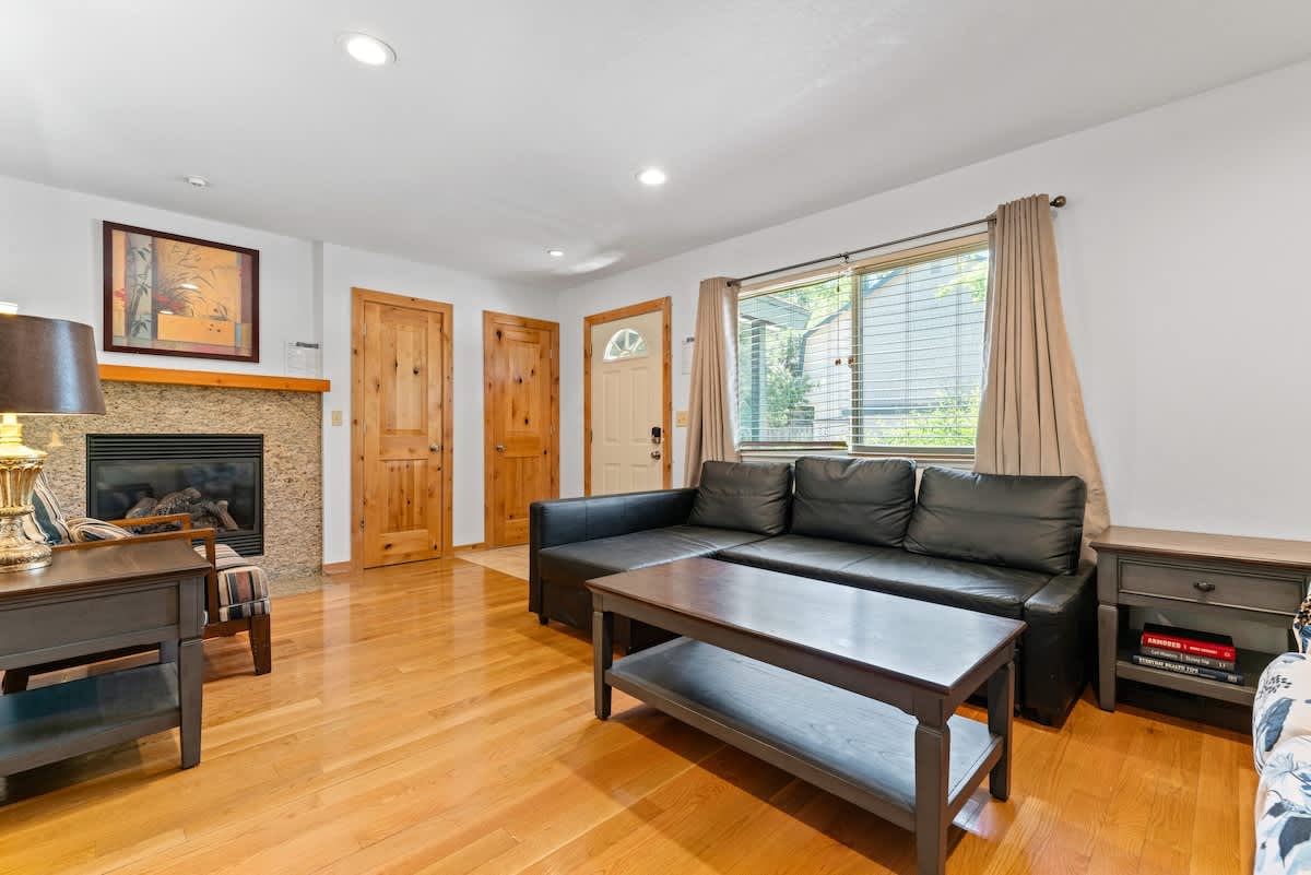 Cozy living room in Tahoe City vacation rental with fireplace, wooden floors, and leather sofa.