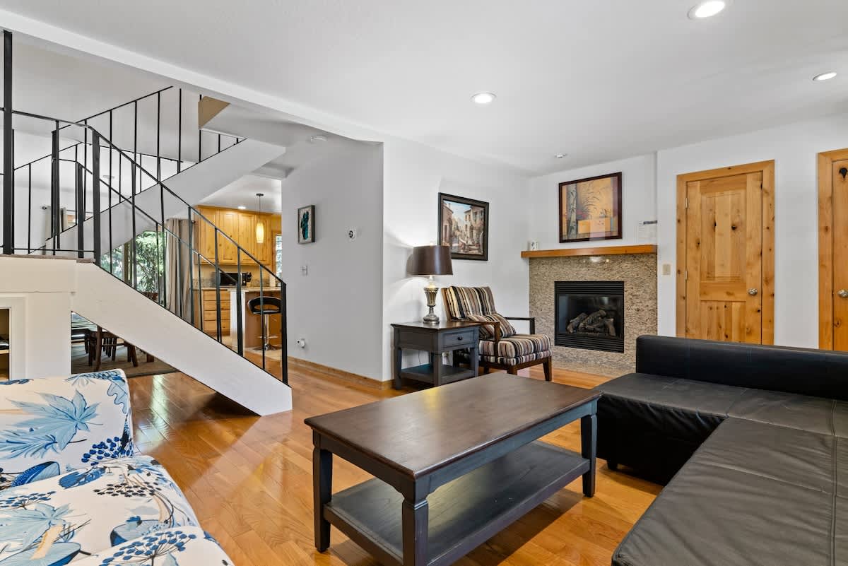 Cozy living room in a Tahoe City vacation rental featuring a fireplace, modern decor, and a spiral staircase.