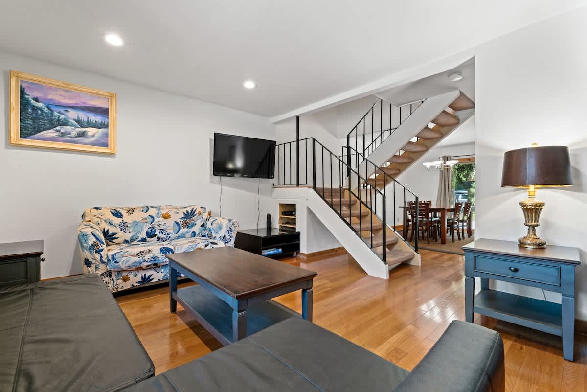 Cozy living room in a Tahoe City vacation rental with a staircase, floral couch, and dining area.