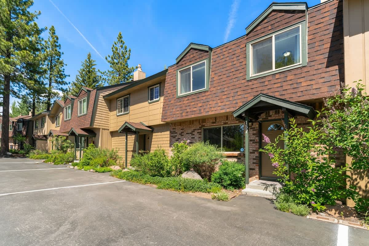 Vacation rental townhouses with brown and beige exteriors nestled among pine trees in Tahoe City.