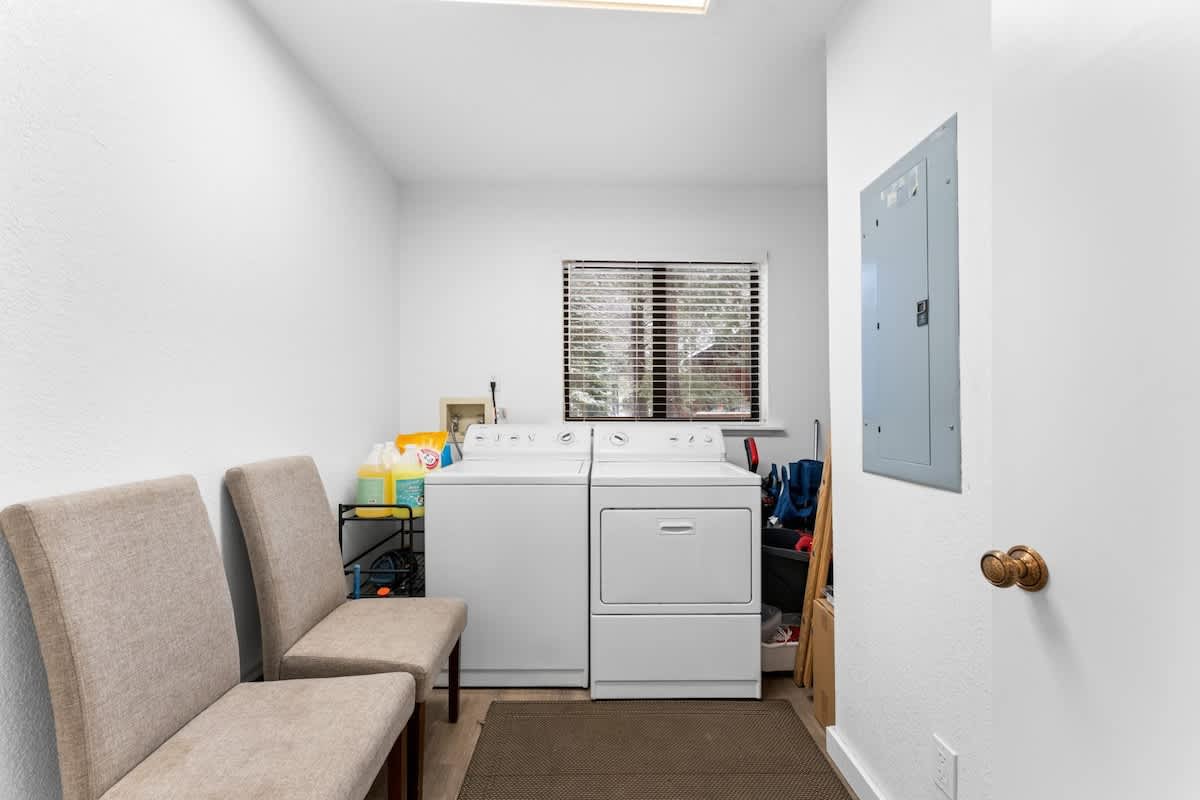 Laundry room in a Truckee vacation rental with washer, dryer, chairs, and cleaning supplies.