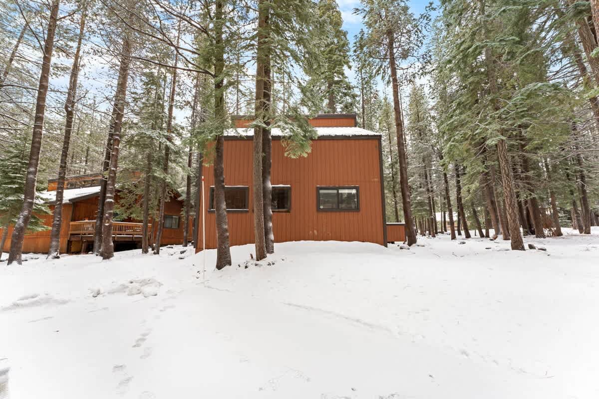 Snow-covered cabin in Truckee, surrounded by trees, ideal vacation rental for a cozy winter getaway.