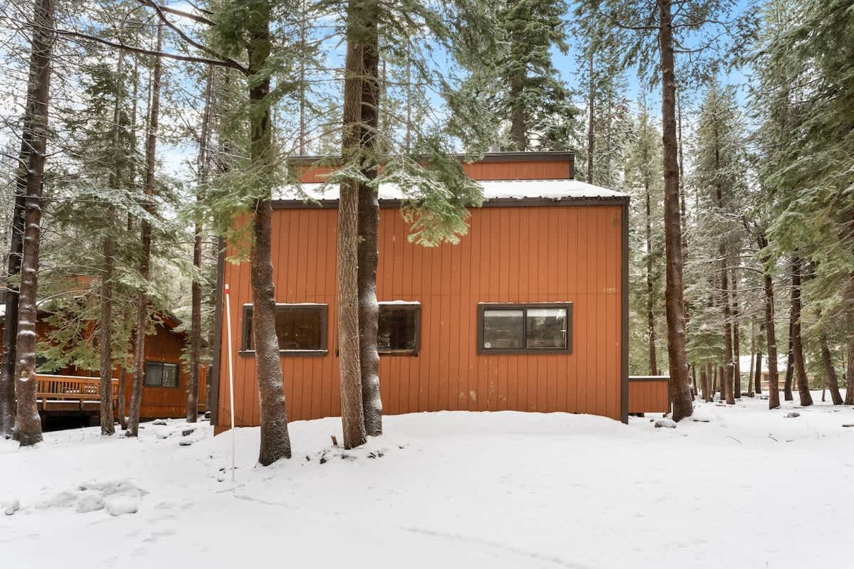 Snow-covered cabin among trees, a vacation rental in Truckee.