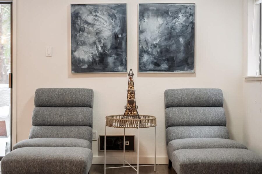 Modern interior of a Truckee vacation rental with two gray chairs, abstract art, and a small Eiffel Tower sculpture.