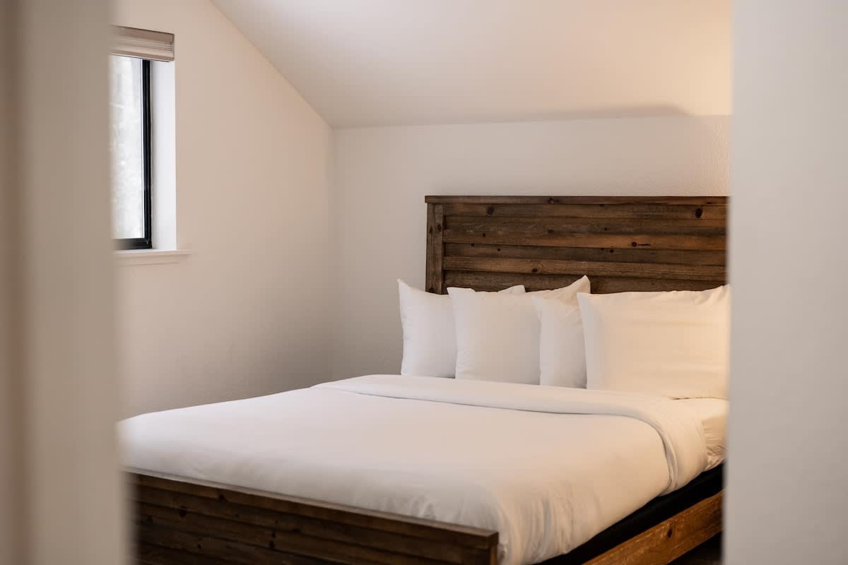 Cozy bedroom in a Truckee vacation rental with a rustic wooden bedframe and white bedding.