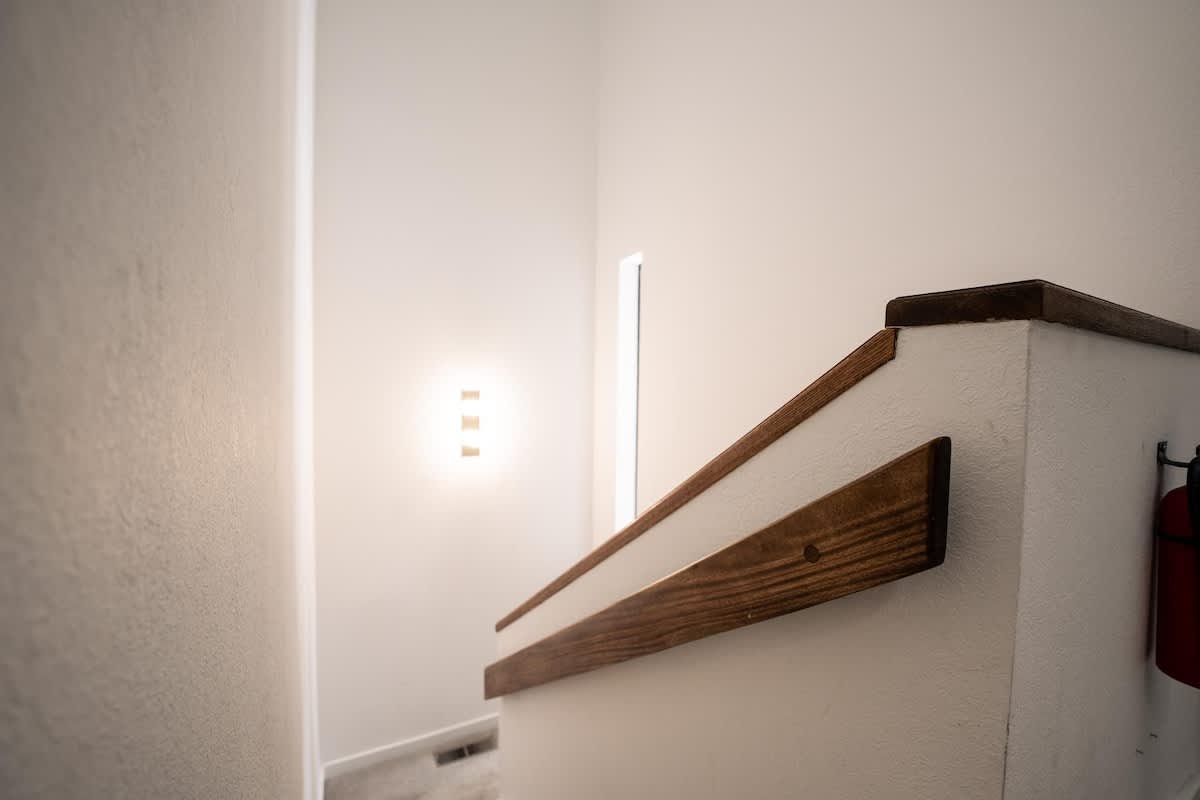 Staircase with wooden handrail in a Truckee vacation rental, featuring modern wall lighting.