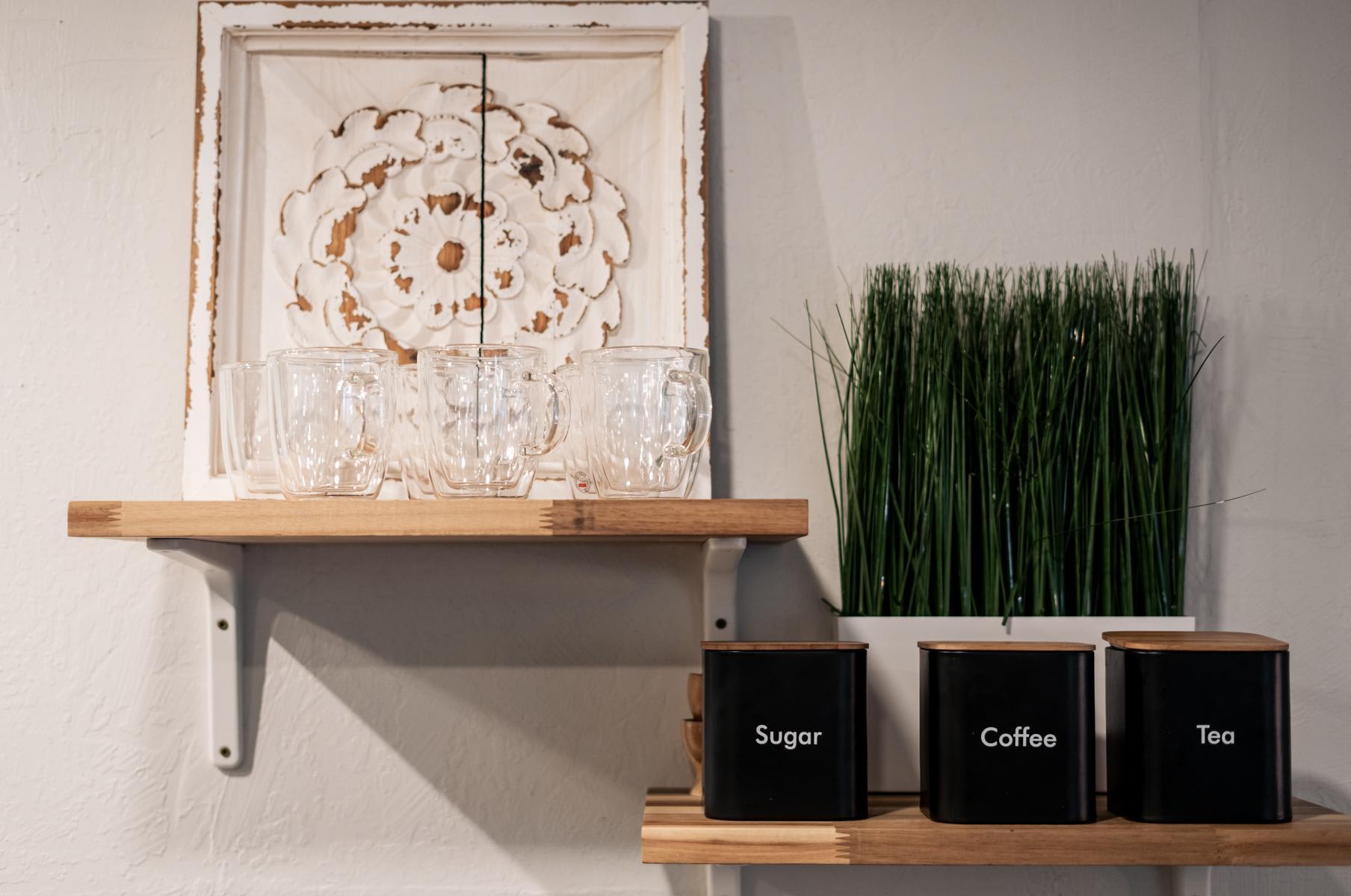 Shelf with glass mugs and containers labeled sugar, coffee, tea in a Tahoe Vista vacation rental kitchen.