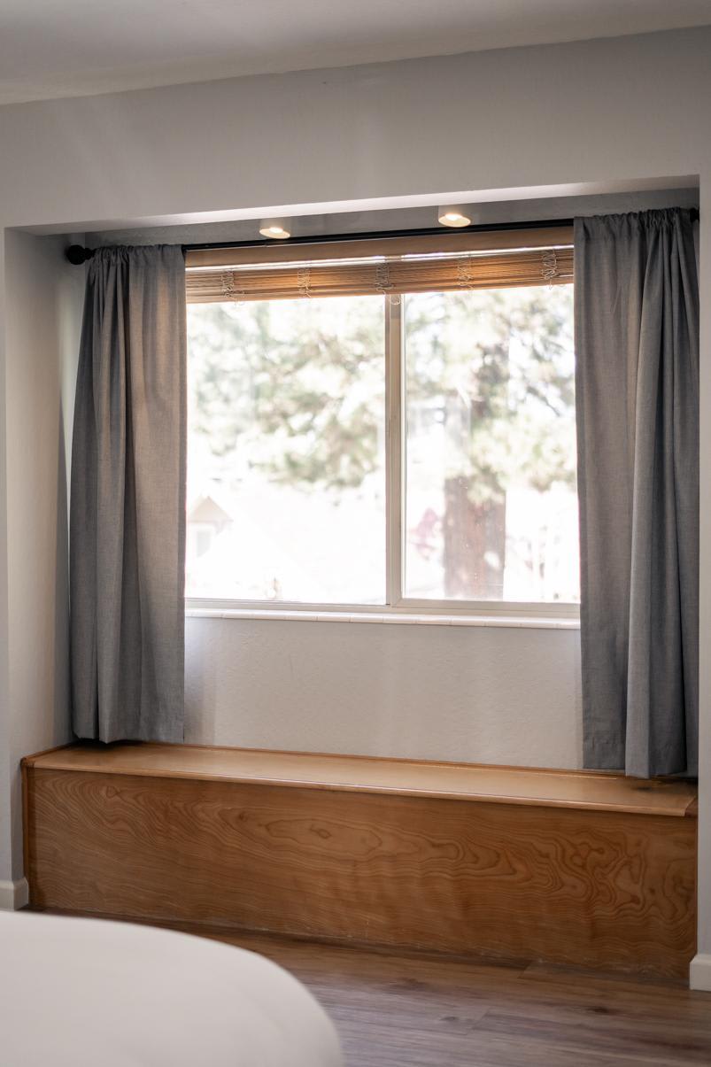 Cozy window seat with gray curtains in a Truckee vacation rental, offering a view of trees outside.