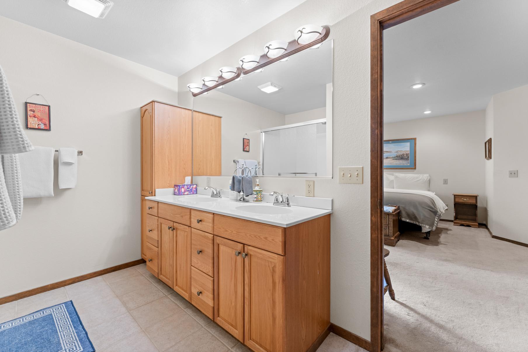 Bathroom and bedroom view in a Truckee vacation rental with double sink vanity and cozy bed setup.