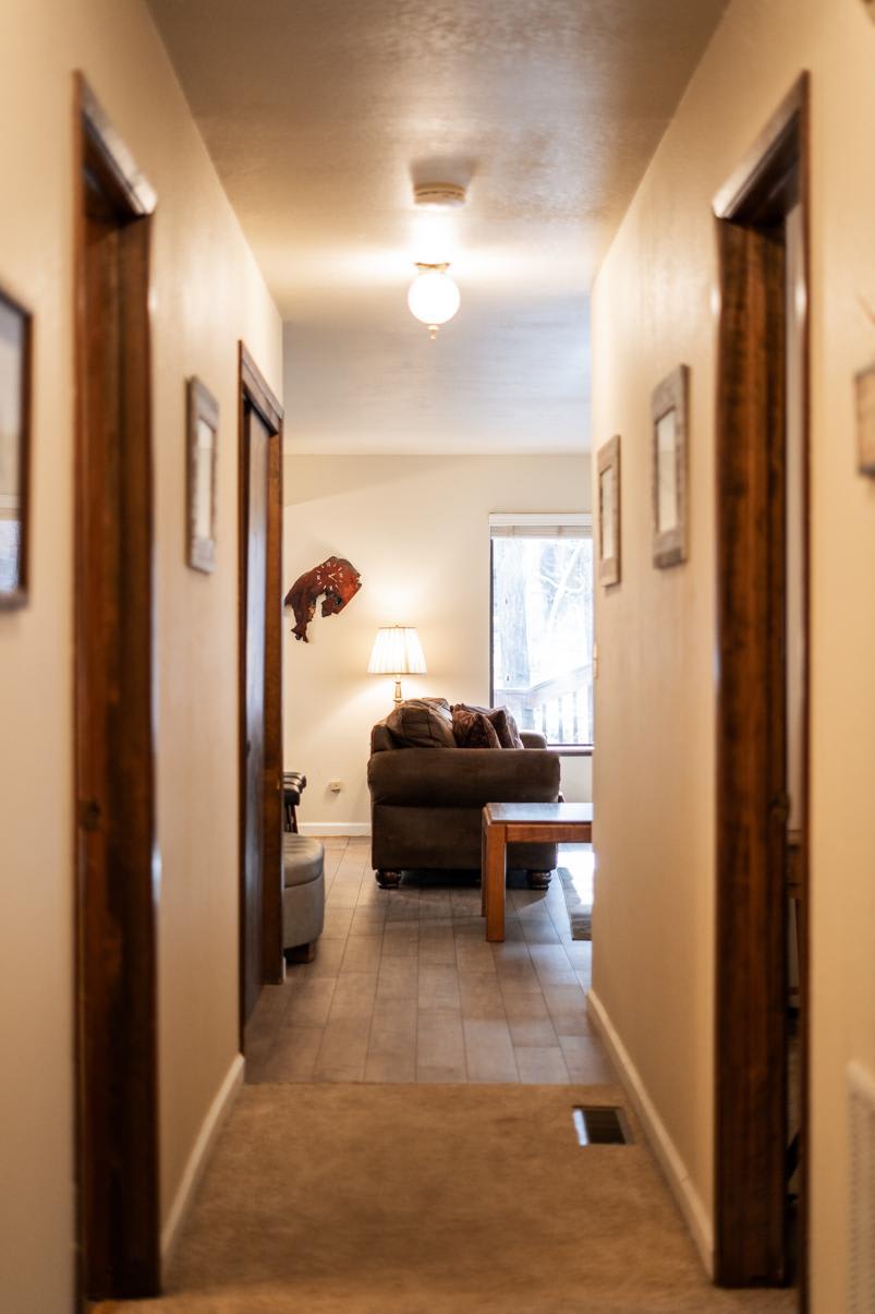 Hallway leading to a cozy living room in a Truckee vacation rental, featuring a sofa, lamp, and wooden coffee table.