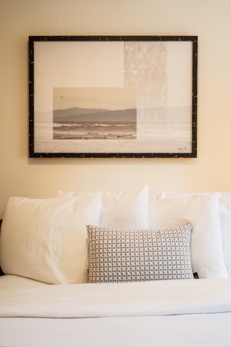 Cozy bedroom in a Truckee vacation rental with a white bed and beach-themed artwork above the headboard.