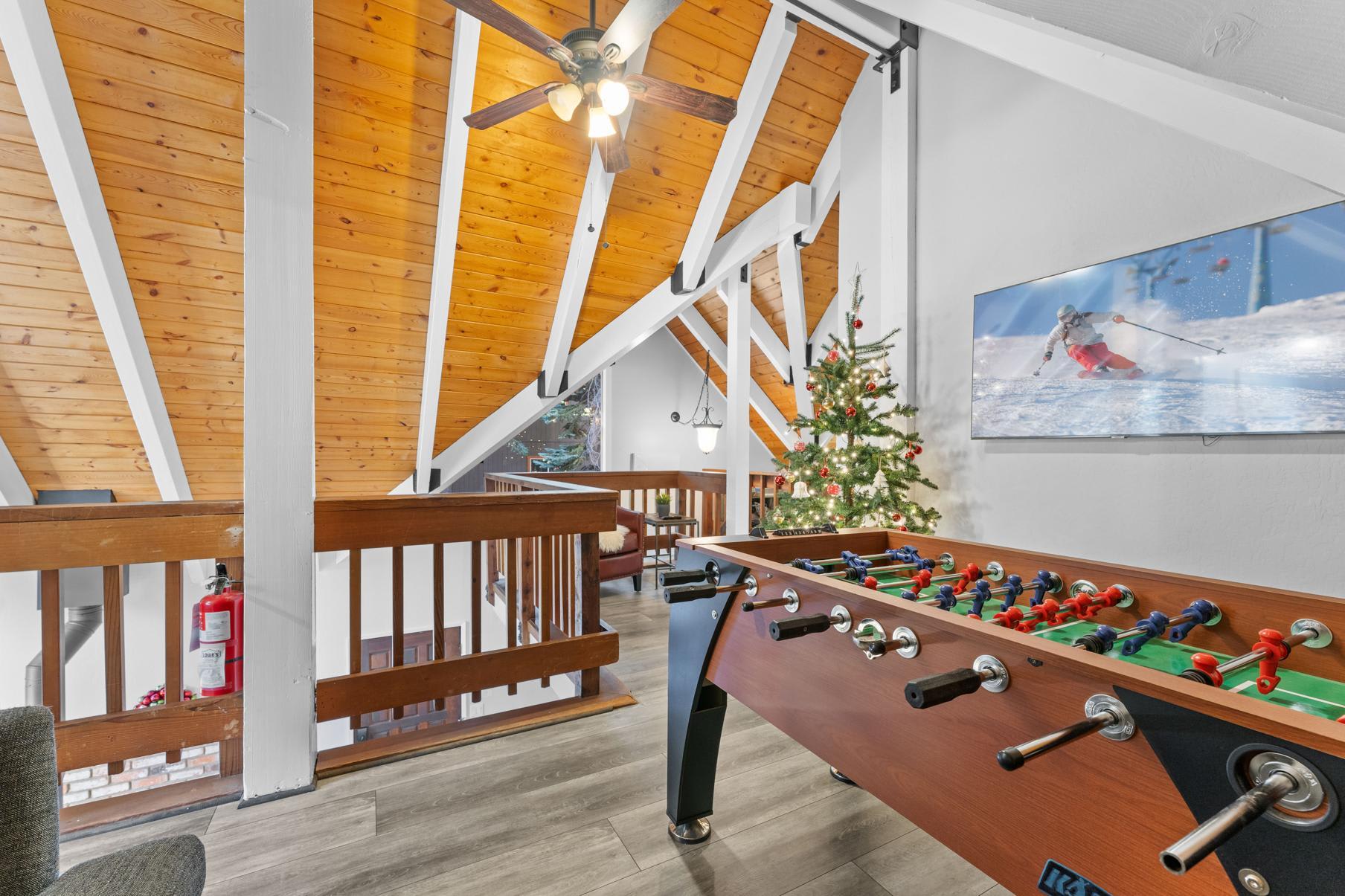 Tahoe Vista vacation rental with wooden beams, foosball table, Christmas tree, and ski-themed wall art.