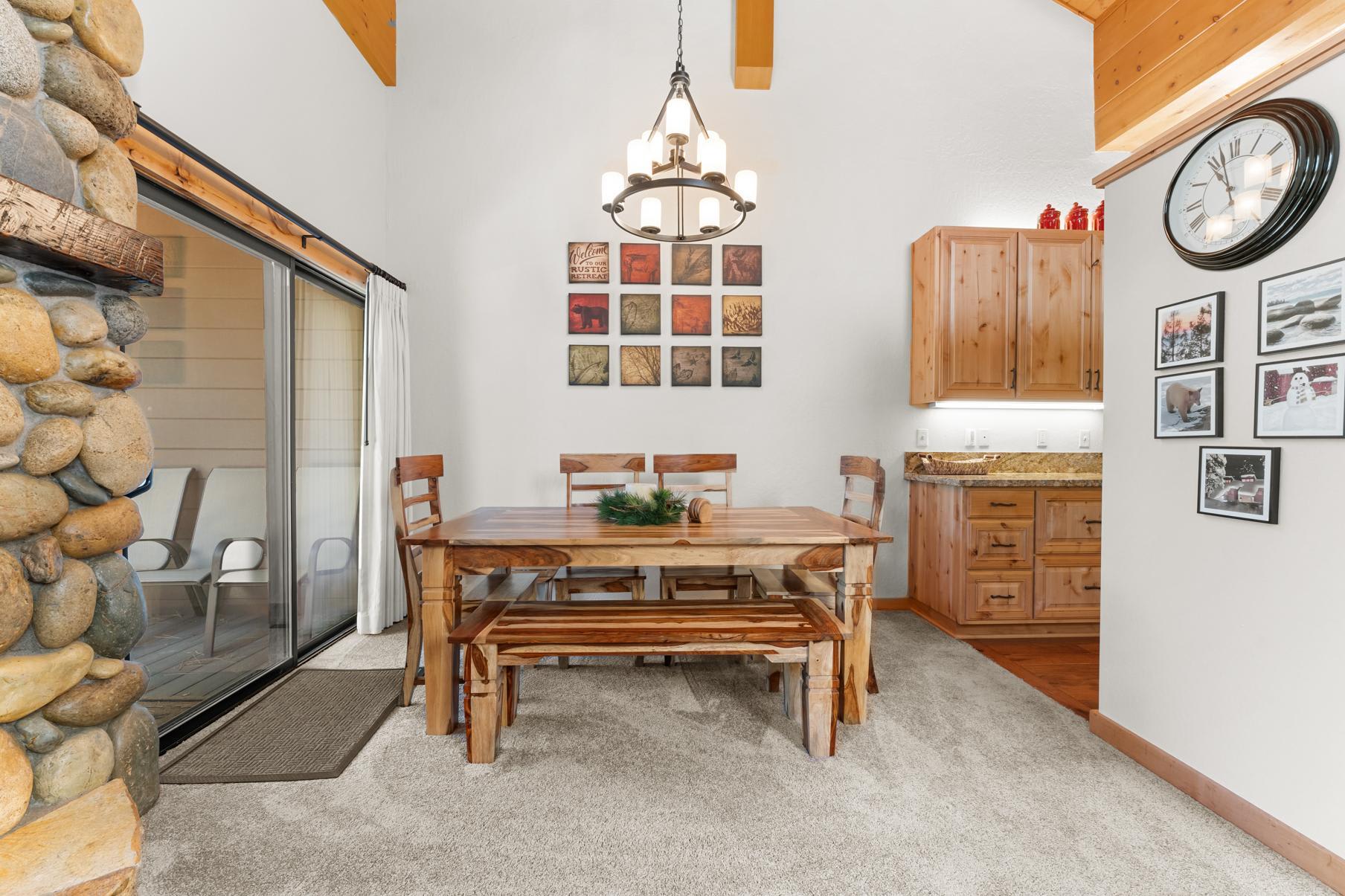 Cozy dining area in Truckee vacation rental with wooden table, stone fireplace, and warm decor.