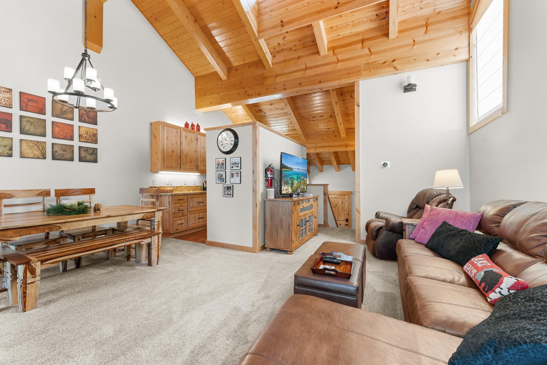 Cozy living room in a Truckee vacation rental with wooden ceiling, leather sofas, and a rustic dining area.