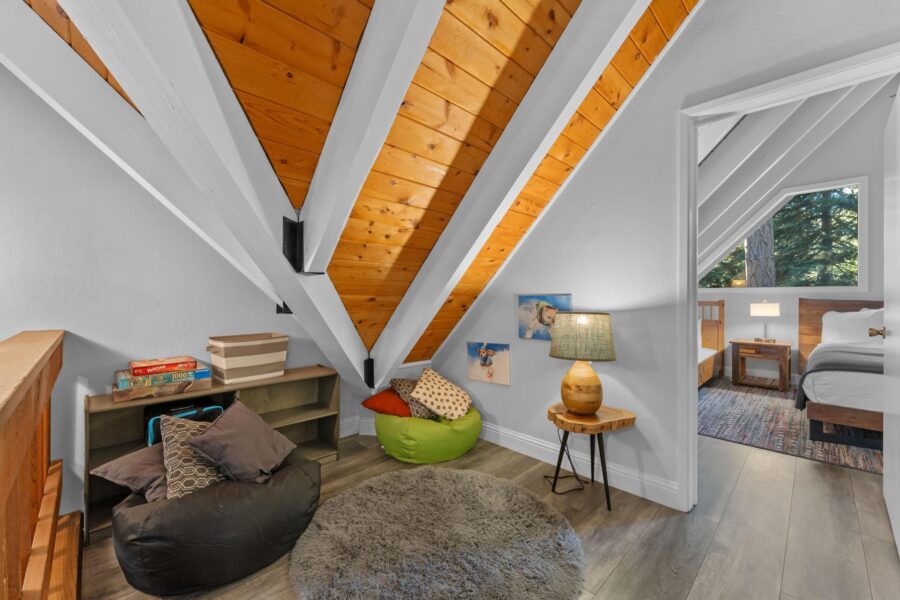 Cozy Tahoe Vista vacation rental loft with bean bags, board games, wood ceiling, and a glimpse of a bedroom with forest view.