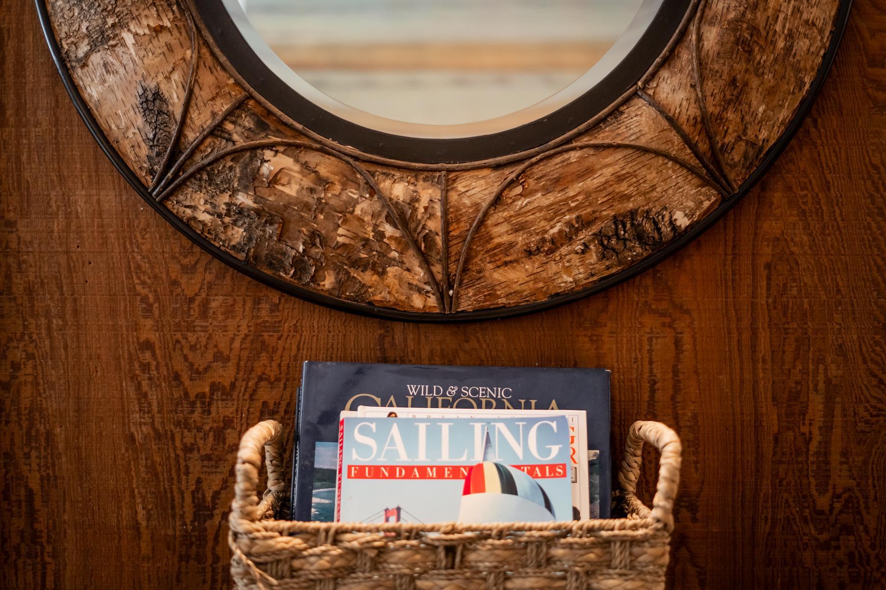 Round mirror and basket of books in a wood-themed Truckee vacation rental.