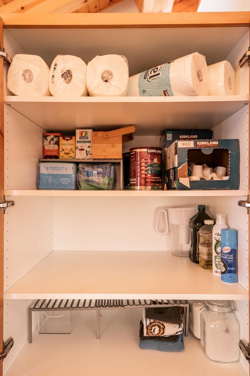 Stocked pantry in a Truckee vacation rental with paper towels, canned goods, and cleaning supplies neatly organized.