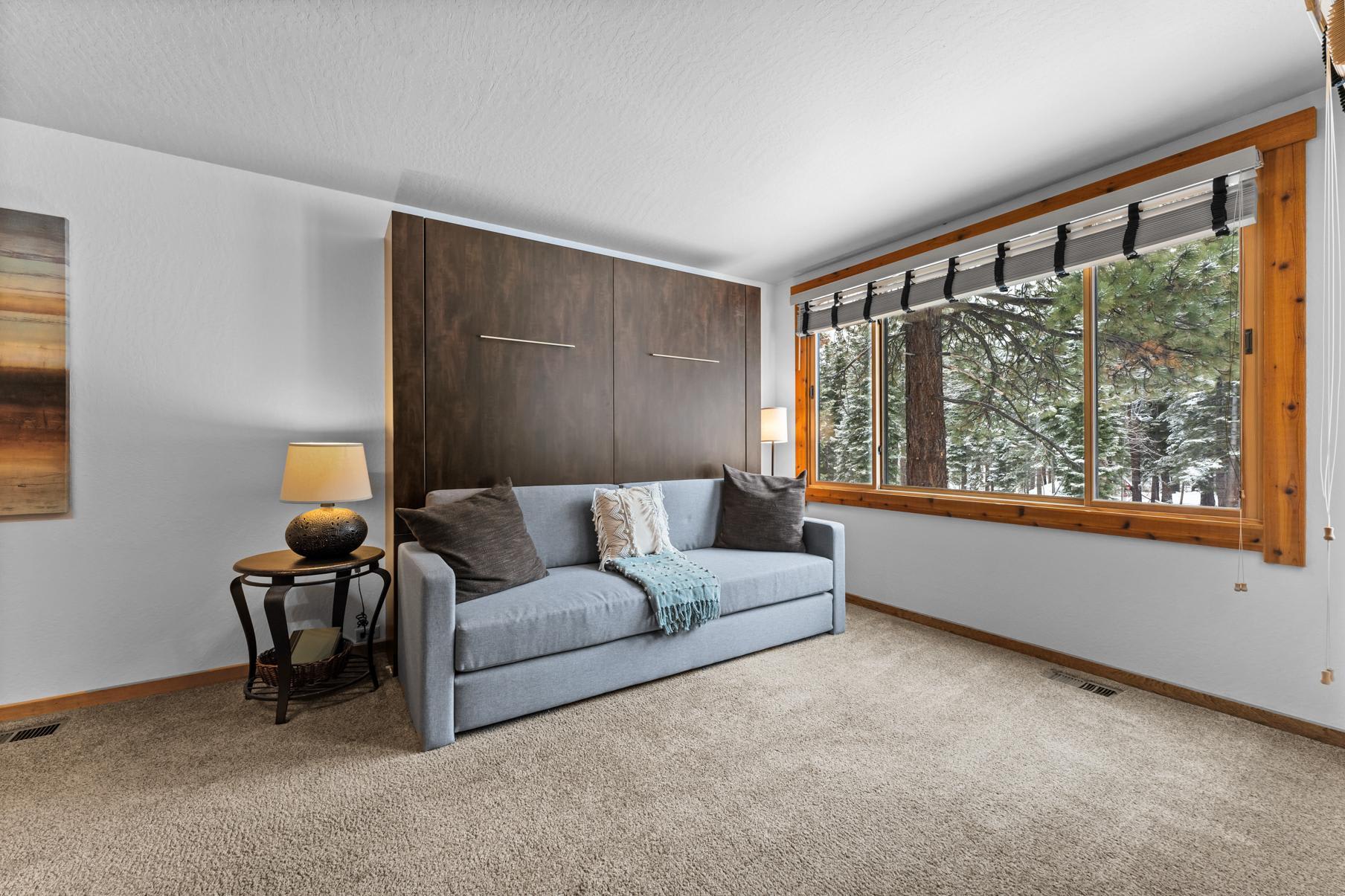 Truckee vacation rental living room with a cozy sofa, large window, and scenic forest view.