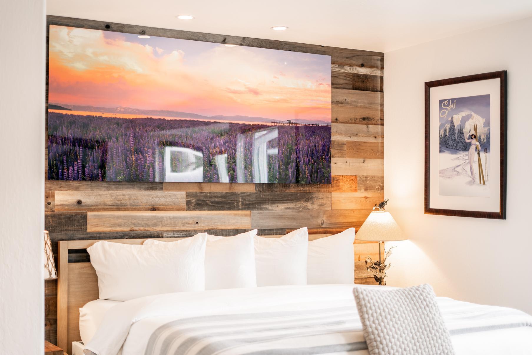 Cozy bedroom in Truckee vacation rental with rustic decor and art, featuring a sunset landscape above the bed.