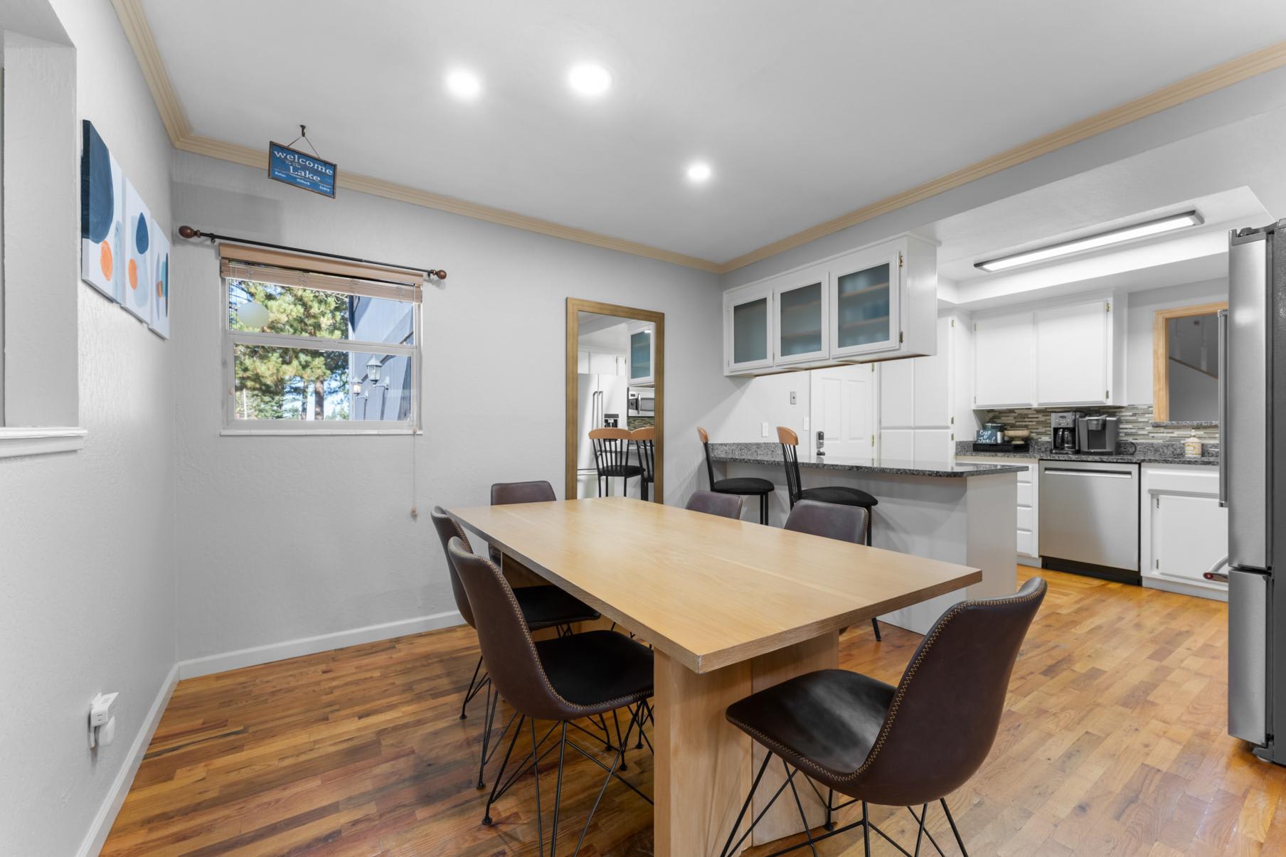 Modern kitchen and dining area in a Truckee vacation rental, featuring sleek furnishings and wooden flooring.