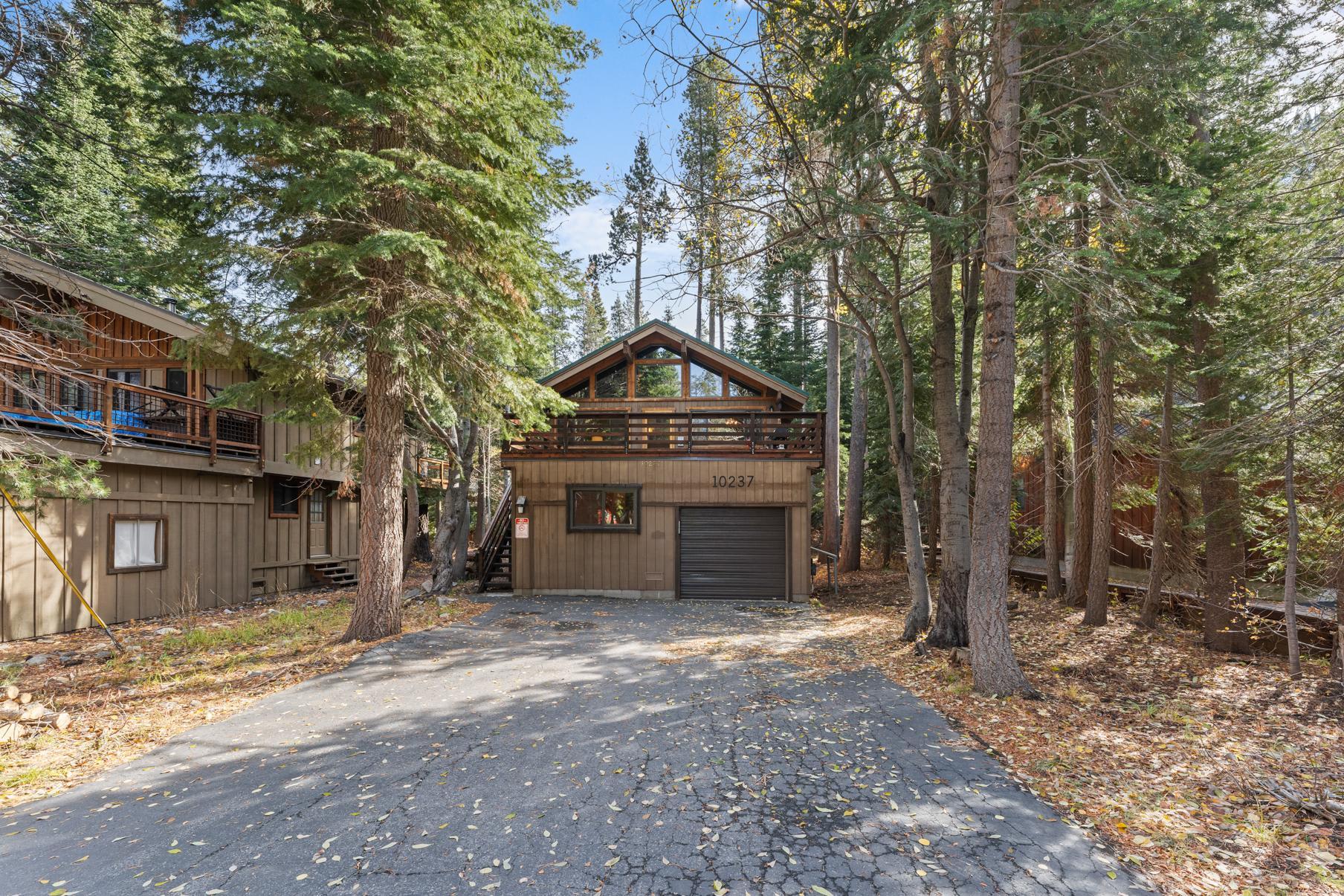 Cozy cabin-style vacation rental in the forested area of Truckee with a wooden exterior and a spacious driveway.