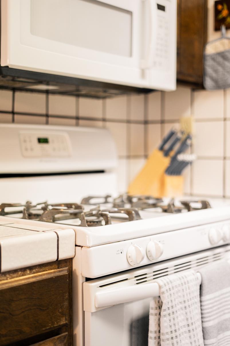 Cozy kitchen in a Truckee vacation rental featuring a white stove and microwave with wooden cabinets and tiled backsplash.